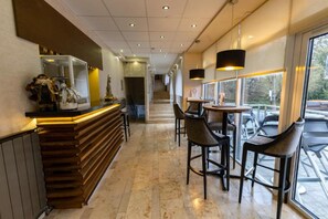 A modern bar area with a wooden counter, bar stools, and pendant lighting. - Bastya Wellness Hotel (Miskolc)