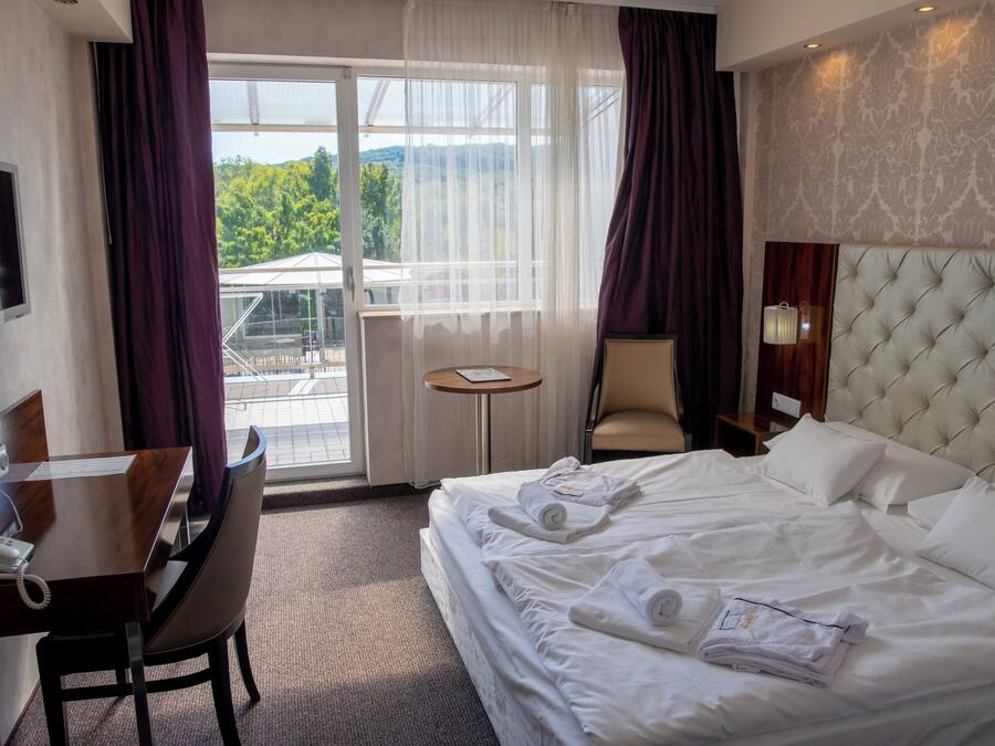 Habitación de hotel con cama, escritorio, silla, mesita y televisor.