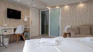 A hotel room with a bed, a desk, a chair, a television, and a sliding door to a bathroom. - Bastya Wellness Hotel (Miskolc)