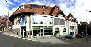 A building with a curved roof, large windows, and a green awning. - Bastya Wellness Hotel (Miskolc)