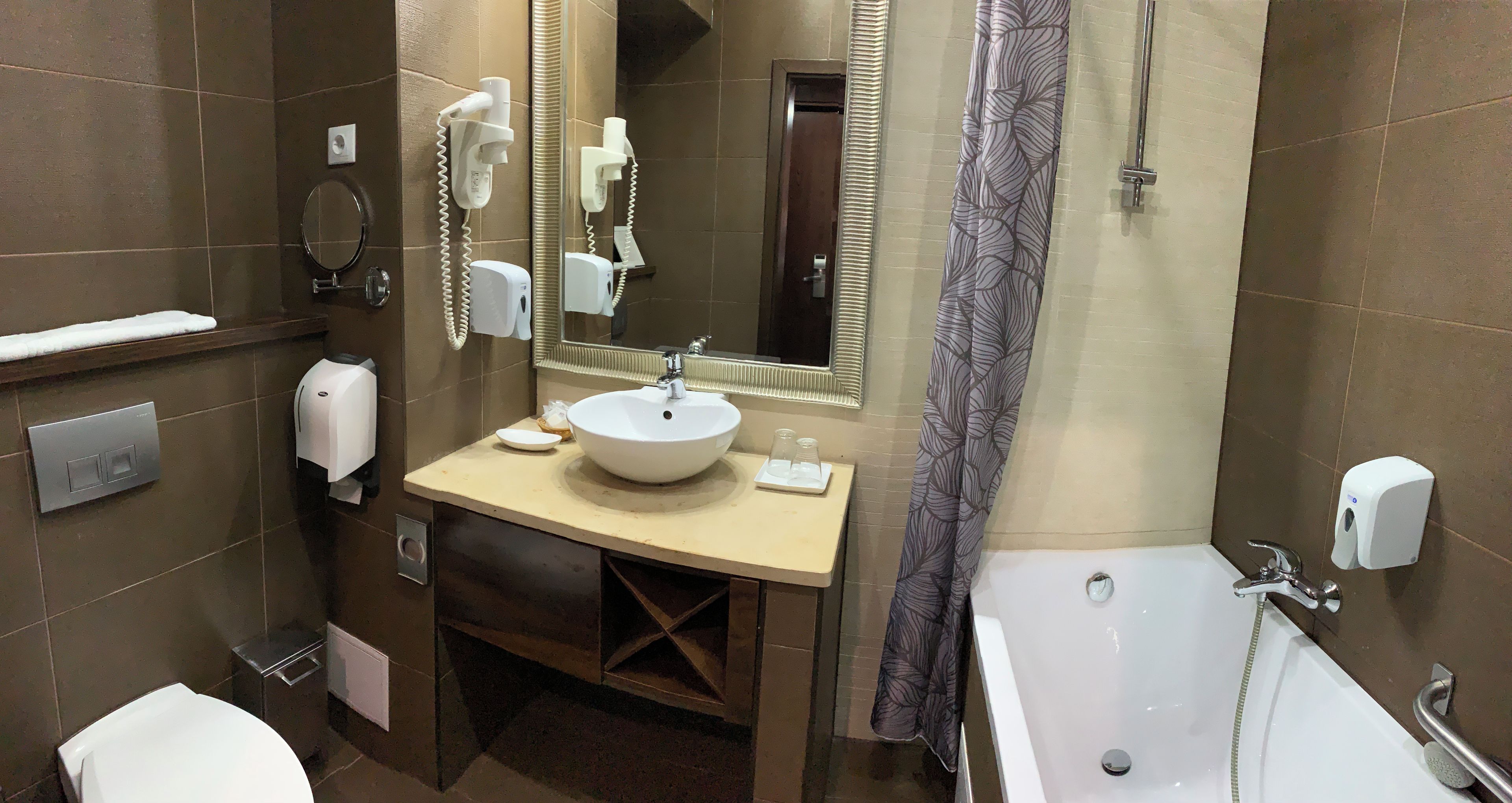 A bathroom with a sink, mirror, towel rack, toilet, and a bathtub.