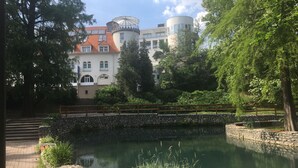 A serene courtyard with a pond, stone walls, and a wooden bridge. - Bastya Wellness Hotel (Miskolc)
