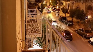 Vista nocturna desde un balcón con vista a una calle con coches y edificios.