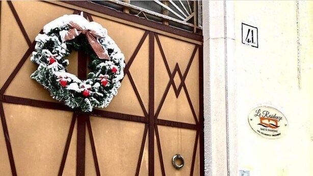 Entrada de hotel con un adorno festivo y un letrero que indica un hospedaje con desayuno.