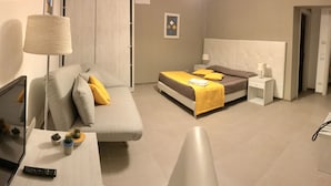 Una habitación de hotel con una cama, un sofá, un televisor y una mesita de noche.
