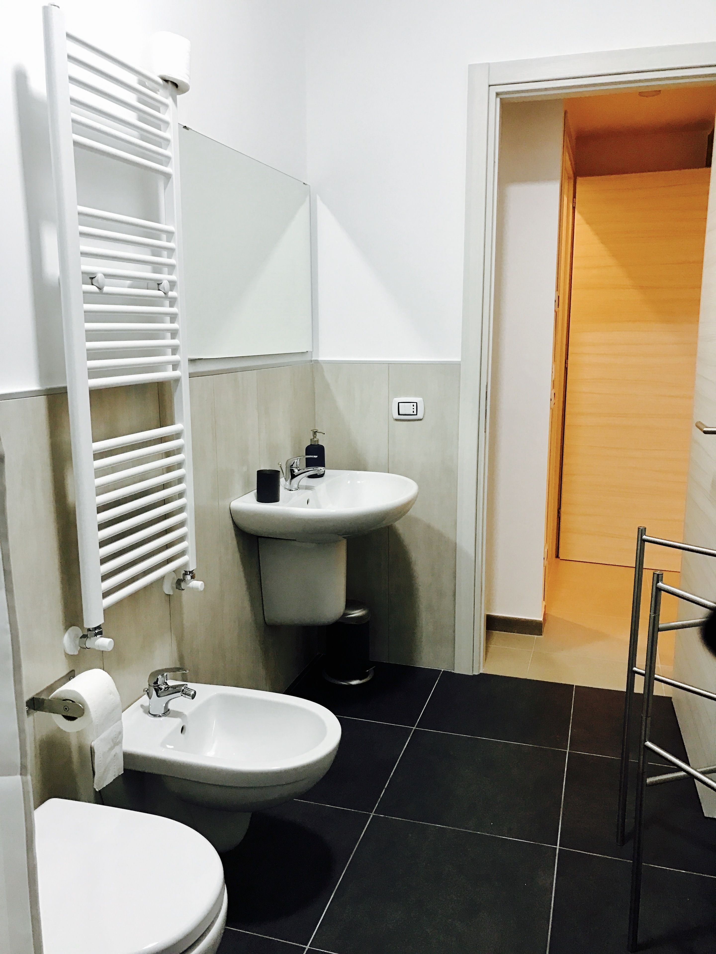 A bathroom with a toilet, bidet, sink, and towel rack.
