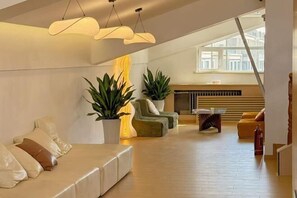 A spacious living area with a high ceiling, a sofa set, a coffee table, and potted plants. - Haolong Hotel (Xining)