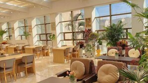 A spacious hotel lobby with multiple seating areas, large windows, and indoor plants. - Haolong Hotel (Xining)
