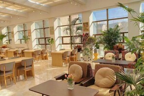 A spacious hotel lobby with multiple seating areas, large windows, and indoor plants. - Haolong Hotel (Xining)