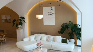 A modern living room with a white sofa, a coffee table with flowers, and large plants. - Haolong Hotel (Xining)