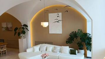 Una sala de estar moderna con un sofá blanco, una mesa de centro con flores y plantas grandes.