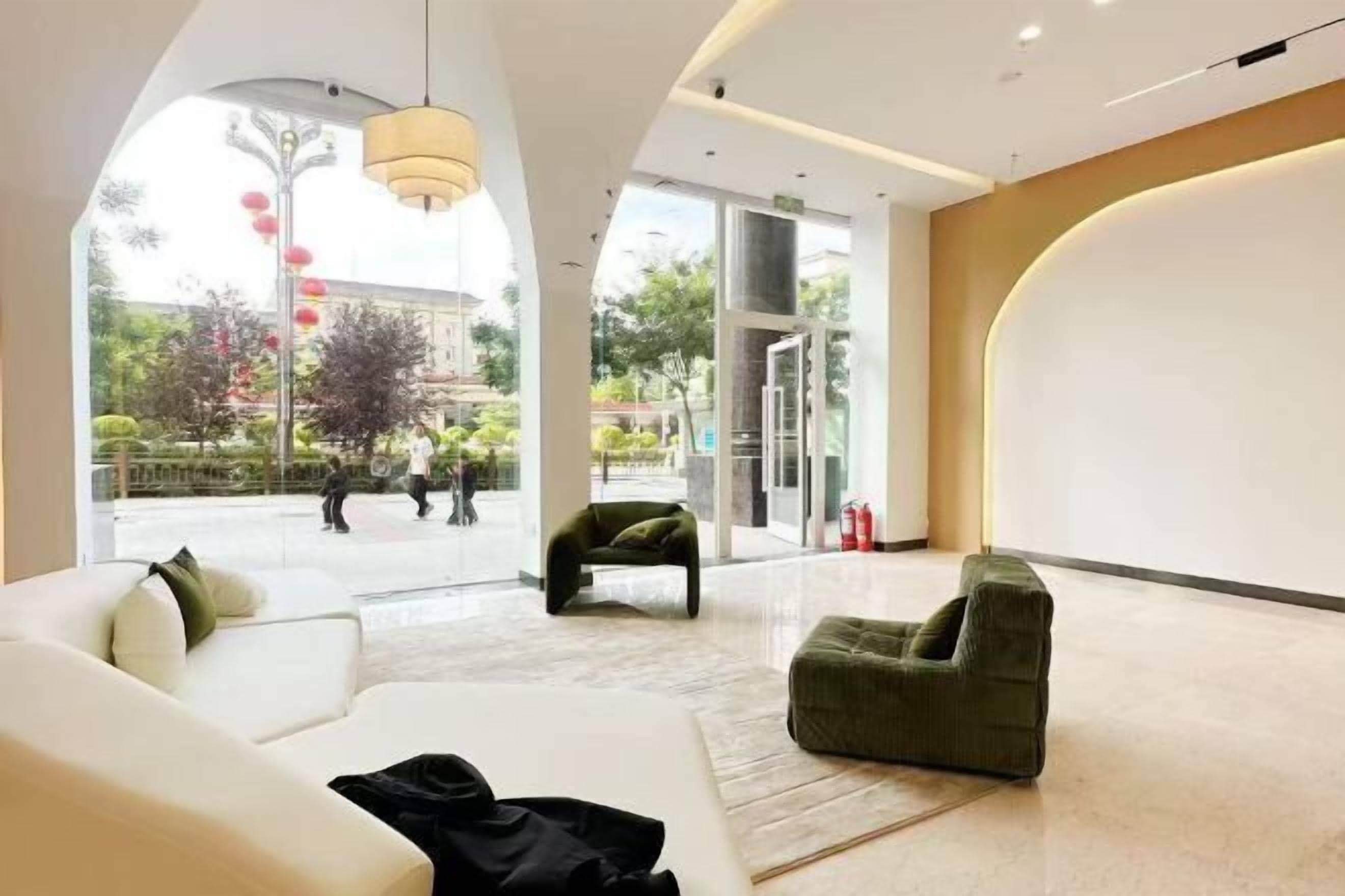 Un lobby moderno de hotel con un amplio espacio de asientos, entrada de vidrio y vistas al exterior.