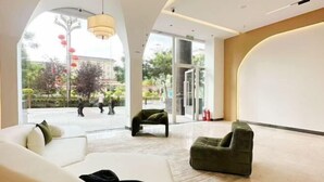 A modern hotel lobby with a large seating area, a glass entrance, and a view of the outside. - Haolong Hotel (Xining)