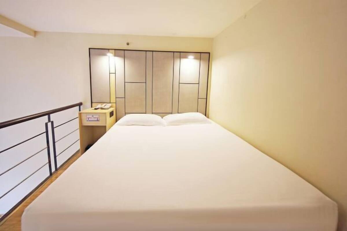 A hotel room with a bed, bedside table, and a nightstand with a phone.