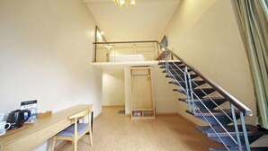 A room with a wooden desk, a chair, a staircase with a metal railing, and a chandelier. - Rest Motel (Xincheng Road) (WENZHOU)