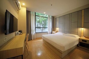 A hotel room with a bed, bedside tables, a desk with a flat-screen TV, a window with curtains, and an air conditioning unit. - Rest Motel (Xincheng Road) (WENZHOU)