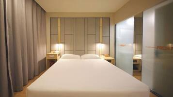 A hotel room with a large bed, two bedside tables, and a mirror on the wall.