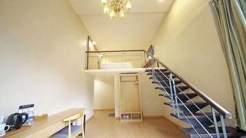 A room with a wooden desk, a chair, a staircase, and a chandelier.