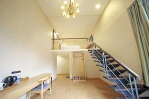 A room with a wooden desk, a chair, a staircase, and a chandelier. - Rest Motel (Xincheng Road) (WENZHOU)