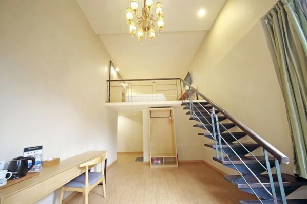 A room with a wooden desk, a chair, a staircase, and a chandelier. - Rest Motel (Xincheng Road) (WENZHOU)
