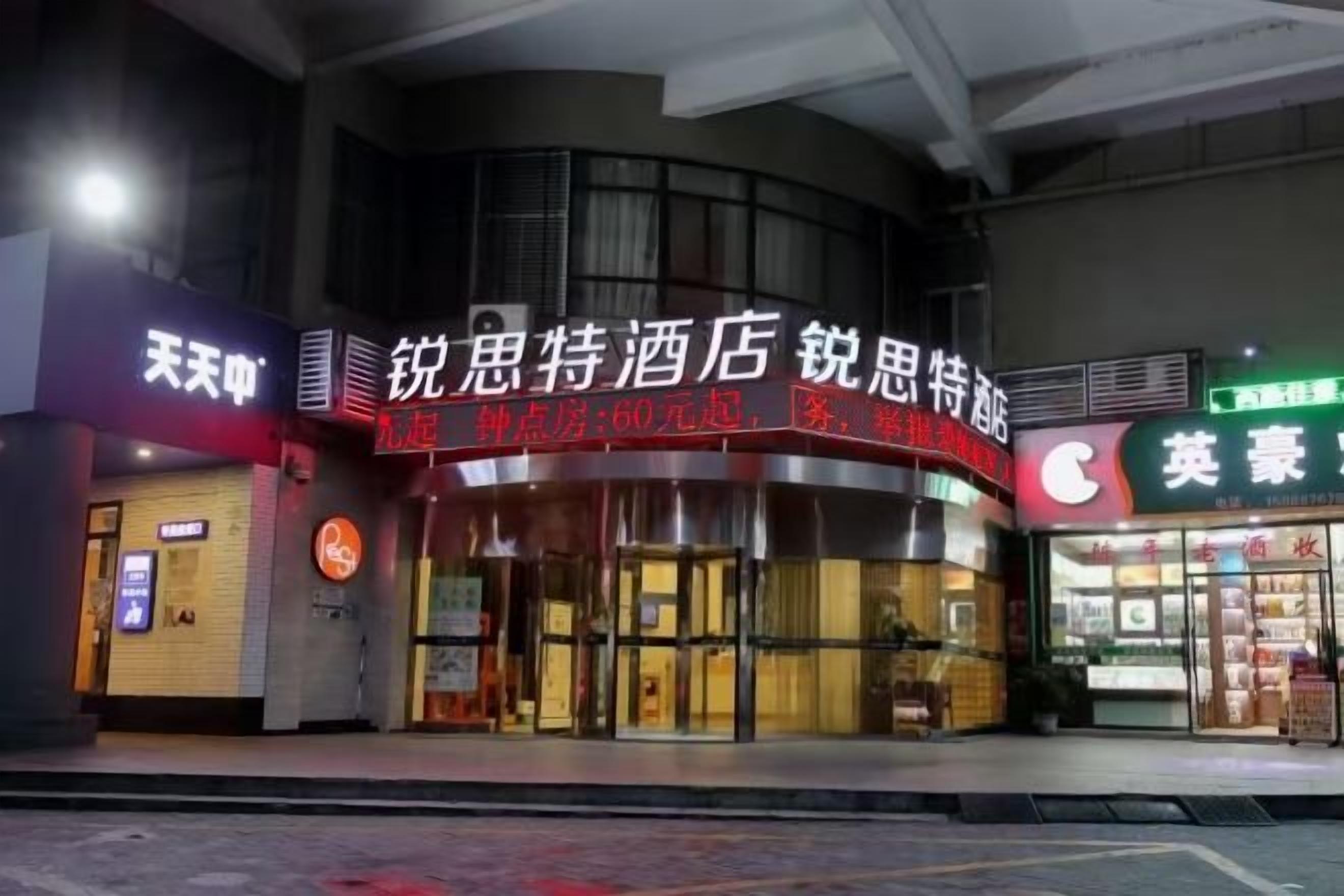 A hotel entrance with a prominent sign, a glass door, and a storefront across the street.