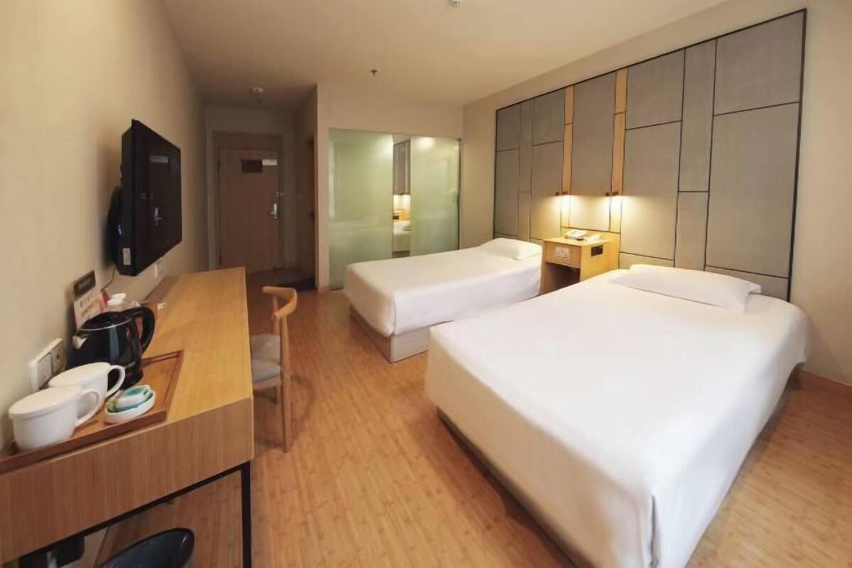 A hotel room with two beds, a desk with a coffee maker, and a TV.