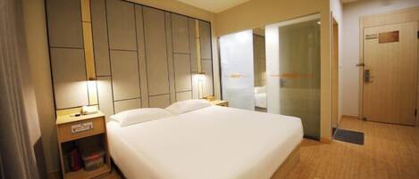 Una habitación de hotel con una cama grande, mesitas de noche, un armario y una puerta.