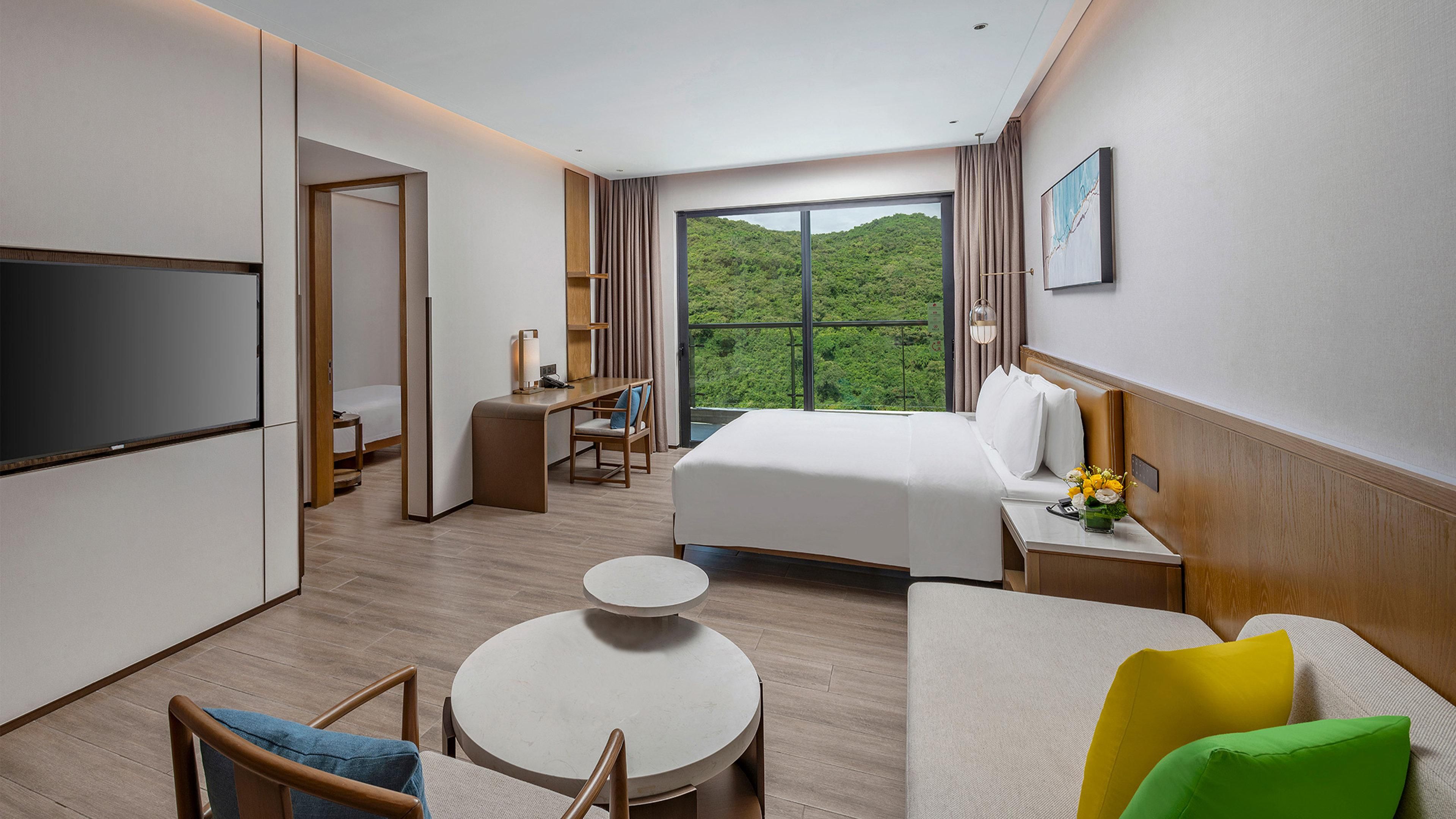 A hotel room with a bed, a desk, a TV, a small round table, and a sofa.