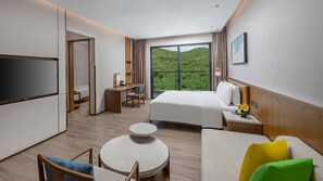 Una habitación de hotel con cama, escritorio, televisor, una mesita redonda y sofá.