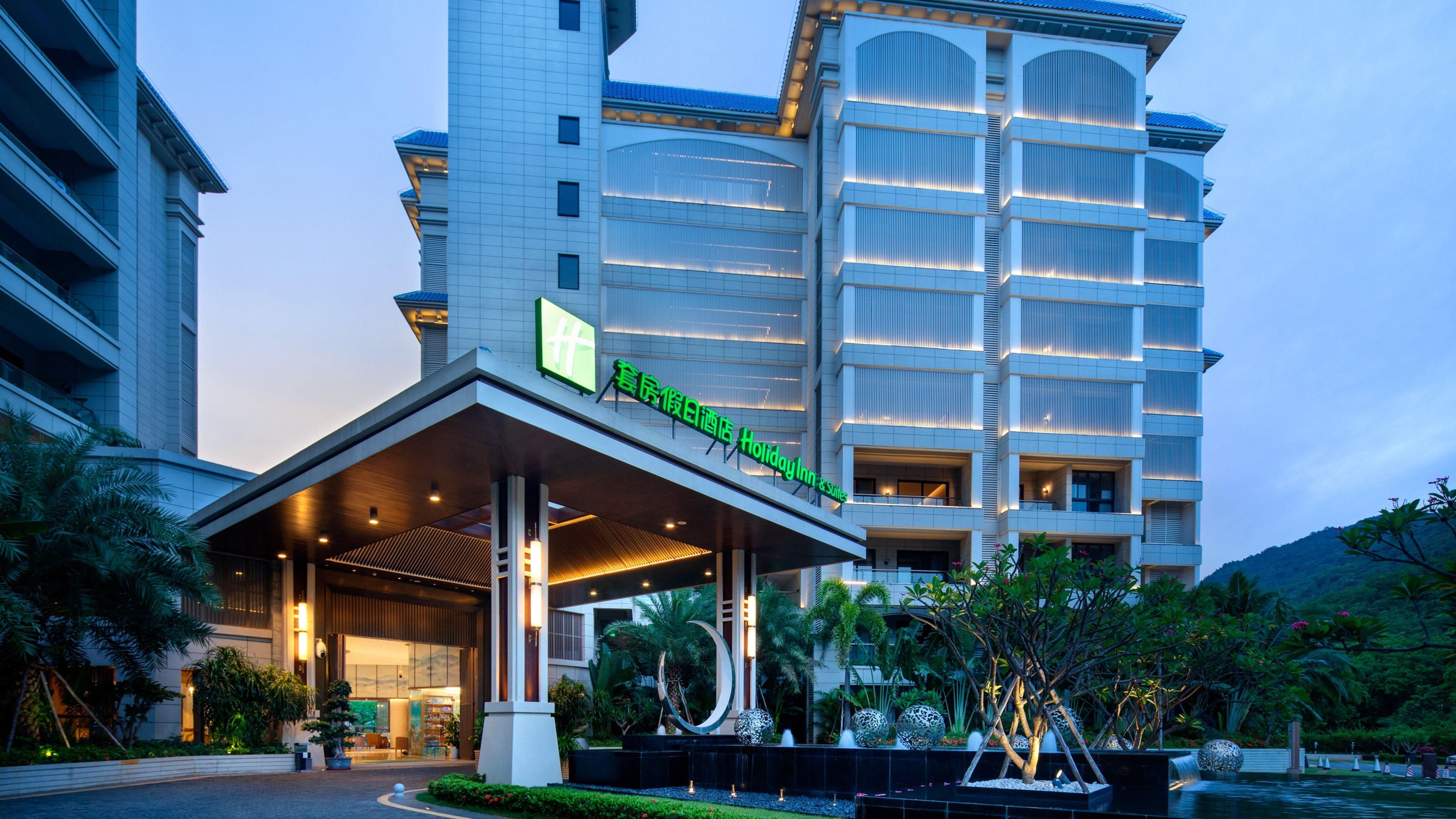 A modern hotel with a prominent entrance, large windows, and a well-maintained garden area.