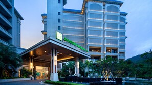 A modern hotel with a prominent entrance, large windows, and a well-maintained garden area. - Holiday Inn and Suites Sanya Yalong Bay (Sanya)