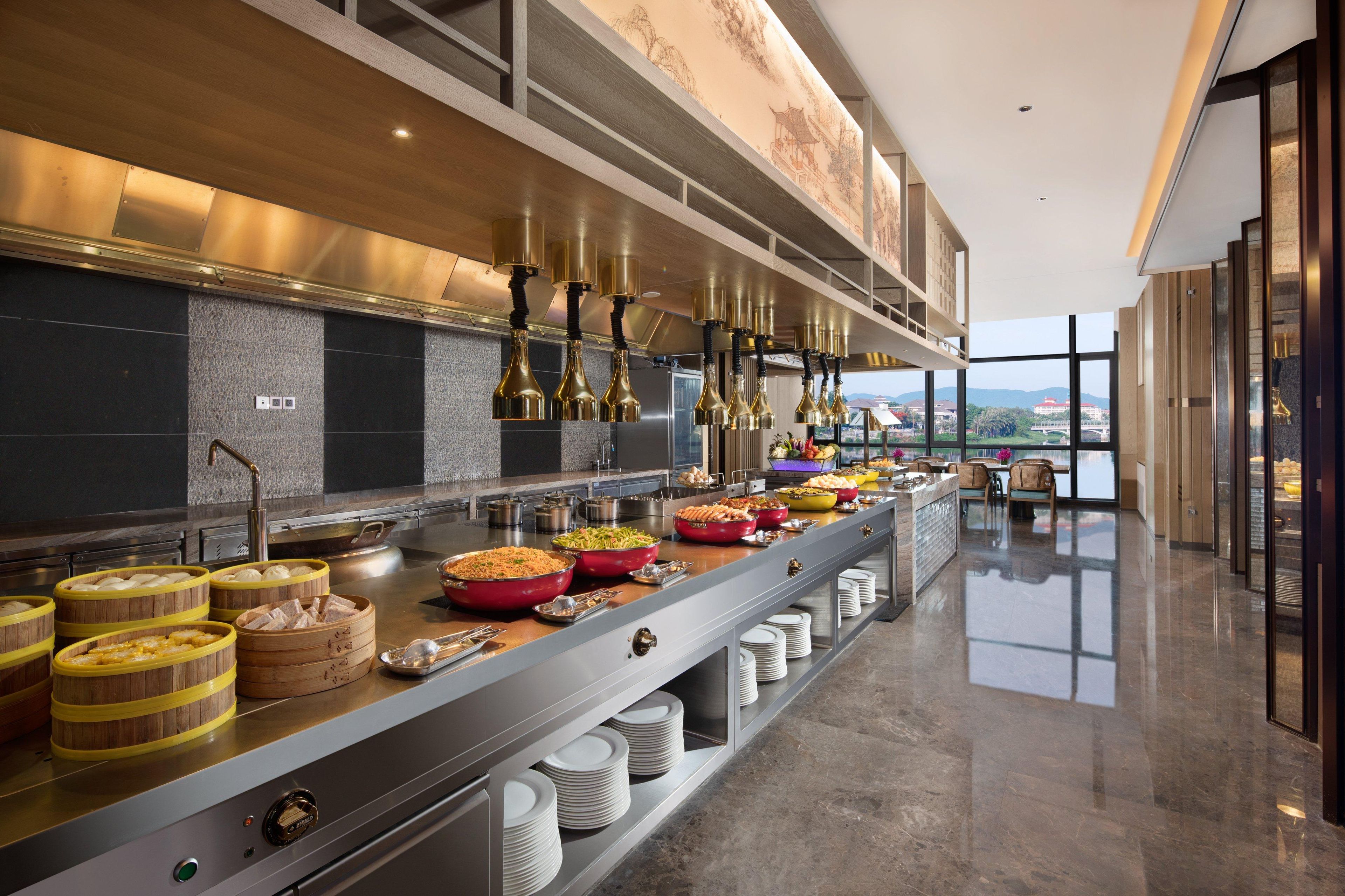 A modern kitchen with stainless steel appliances, wooden serving stations, and a view of the city.