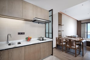 A modern kitchen with a built-in stove, a sink, and a dining area with wooden chairs and a table.