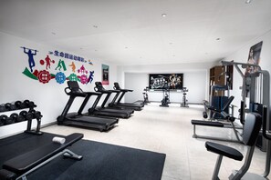 Un gimnasio con cintas de correr, mancuernas y máquinas de pesas.