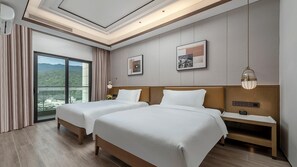 Une chambre d’hôtel avec deux lits, une table de chevet, une lampe et une grande fenêtre donnant sur un beau paysage.
