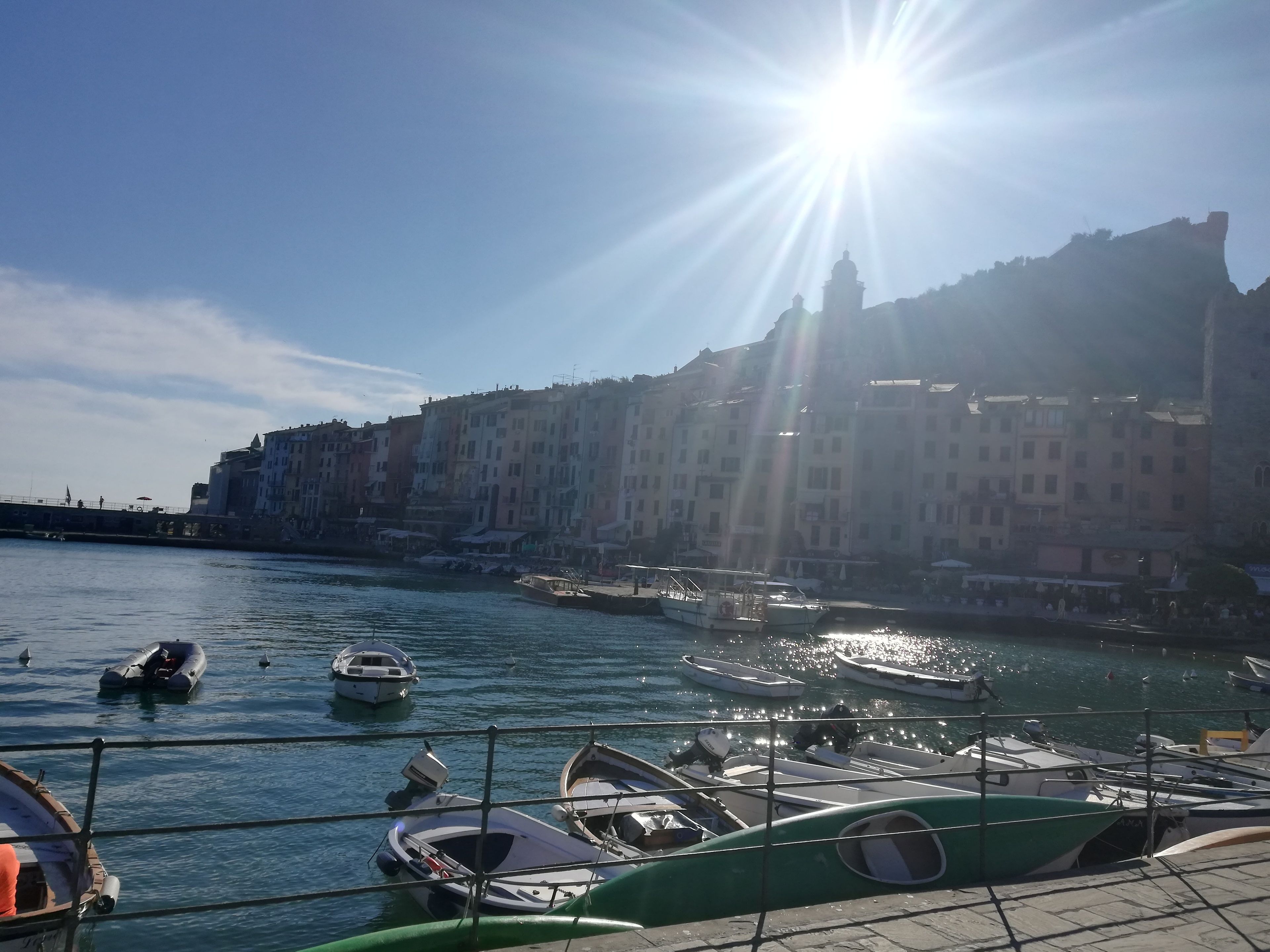 A marina with boats docked, a clear sky, and buildings in the background.