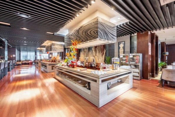 A modern hotel lobby with a central island, bar area, and a high ceiling with a unique design.