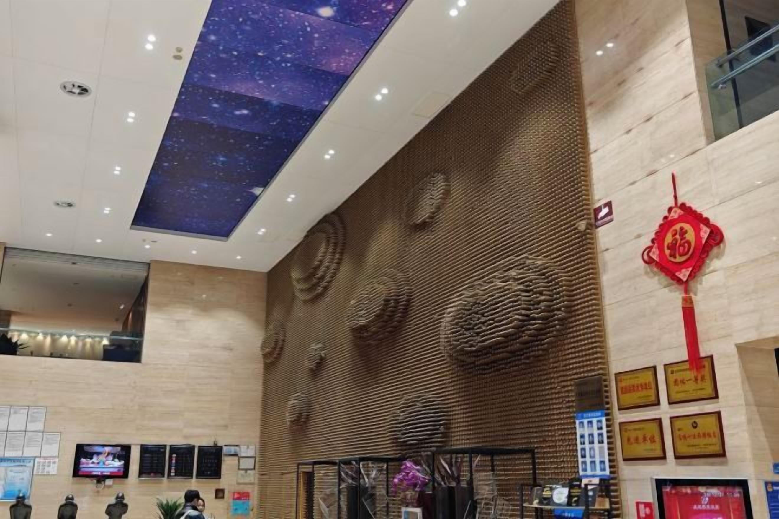 A hotel lobby with a high ceiling, a starry sky projection, a reception desk, and a traditional Chinese decorative element.