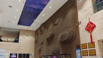 A hotel lobby with a high ceiling, a starry sky projection, a reception desk, and a traditional Chinese decorative element.