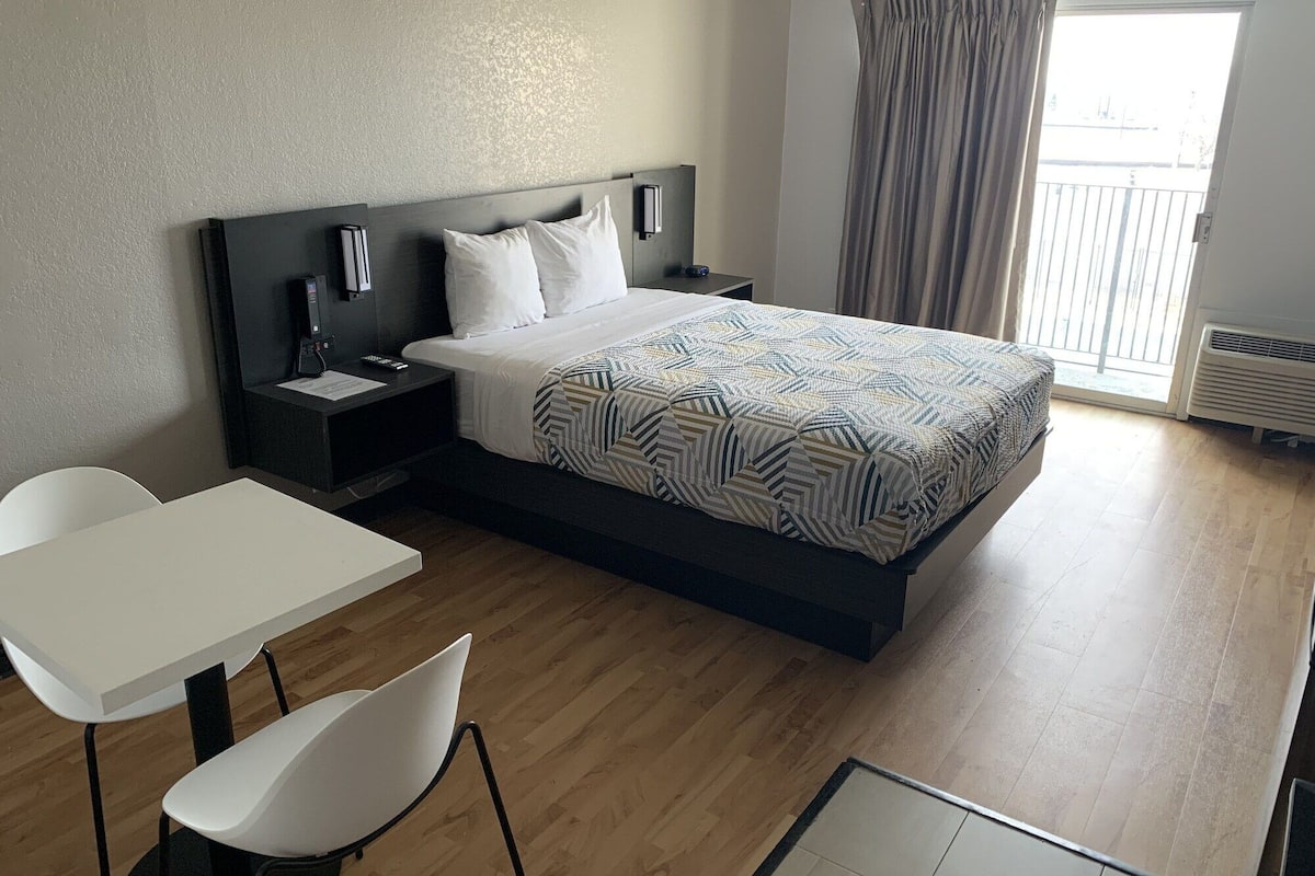 A modern hotel room with a large bed, a desk, and a chair.