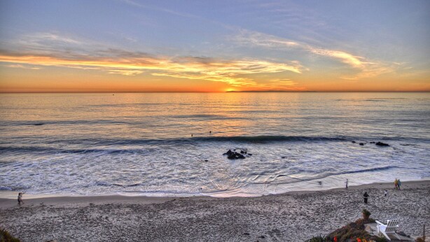 Ein Strand mit Wellen und einem Sonnenuntergang.