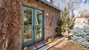 A house with a green door, ivy-covered walls, and a stone fountain in the yard. - Casa Dos Truchas | Adobe Retreat (Santa Fe)
