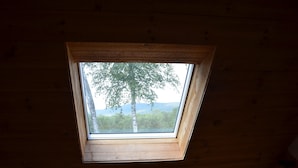 Un tragaluz en un techo de madera con vistas a árboles y montañas.