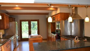 A spacious kitchen with wooden cabinets, granite countertops, stainless steel appliances, and pendant lighting.