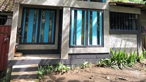 A two-story house with a balcony, large windows, and a wooden roof. - Anne's Place (La Fortuna)