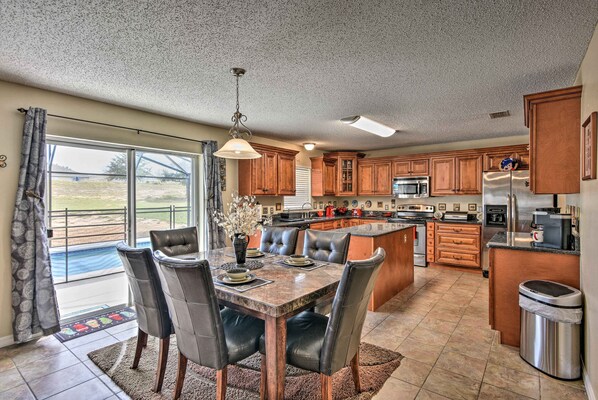 A spacious kitchen with a dining area, featuring a large island, wooden cabinets, and modern appliances.