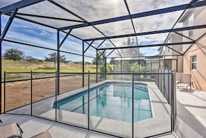 A covered outdoor swimming pool with a view of a residential area and a clear sky.