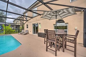 Relax by the pool in a shaded seating area with a table and chairs.