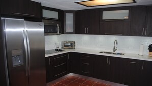 Una cocina moderna con armarios oscuros, electrodomésticos de acero inoxidable y un salpicadero de azulejos.