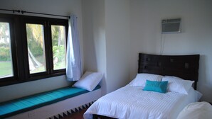 Un dormitorio con cama, un banco y una ventana con cortinas.